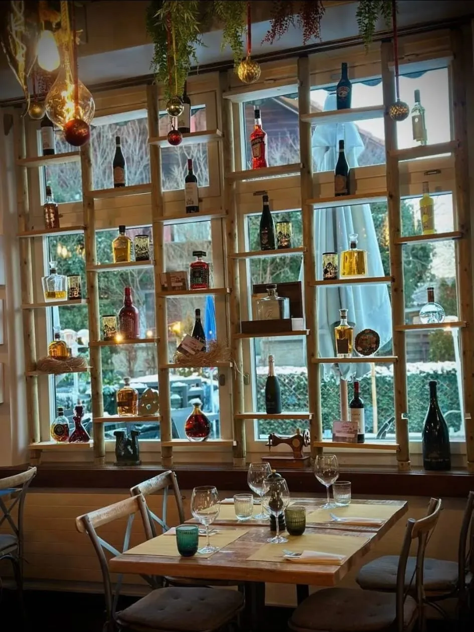 Fensterregal mit Weinflaschen und gedeckten Tischen